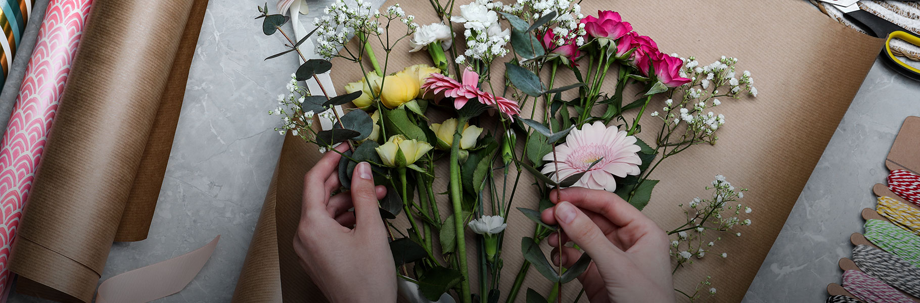 hands arranging flowers on a tabletop