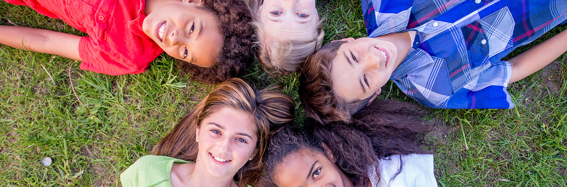 kids from above lying on grass with heads together