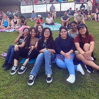 college program students sitting on lawn for music performance in the grove