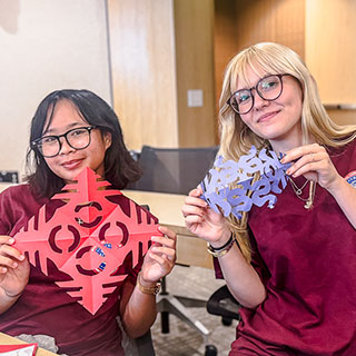 two students holding up chinese craft project in classroom