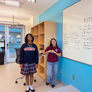 students in classroom posing in front of white board
