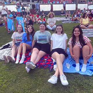 students on lawn in grove at music performance